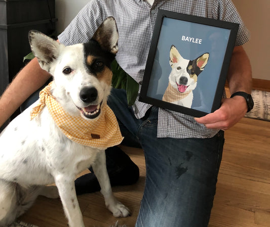 A man kneeling next to his dog while holding a portrait 